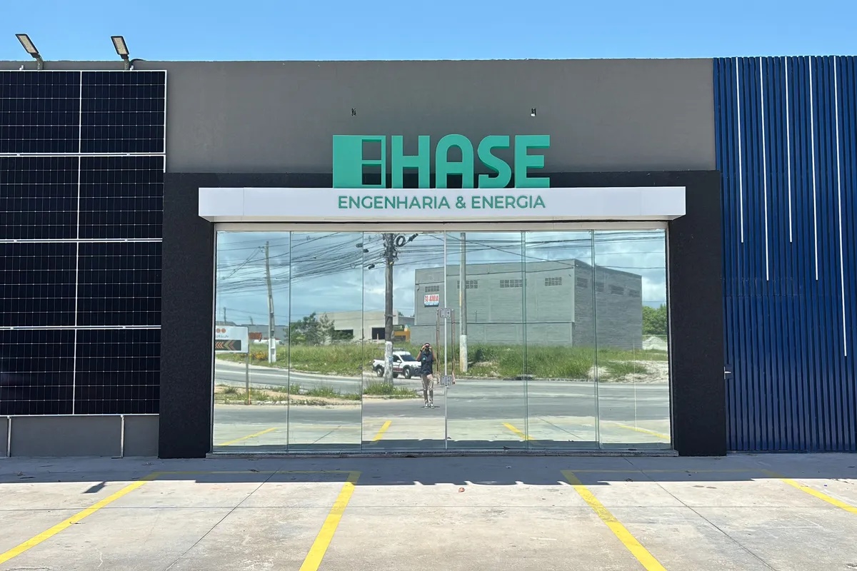 Fachada da unidade HASE em Porto Seguro, BA: letreiro HASE Engenharia & Energia, vitrine de vidro e painéis solares na lateral do prédio.