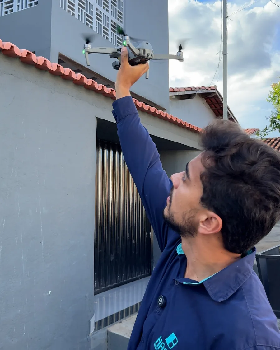 Técnico da HASE lançando o drone ao lado do telhado do imóvel.