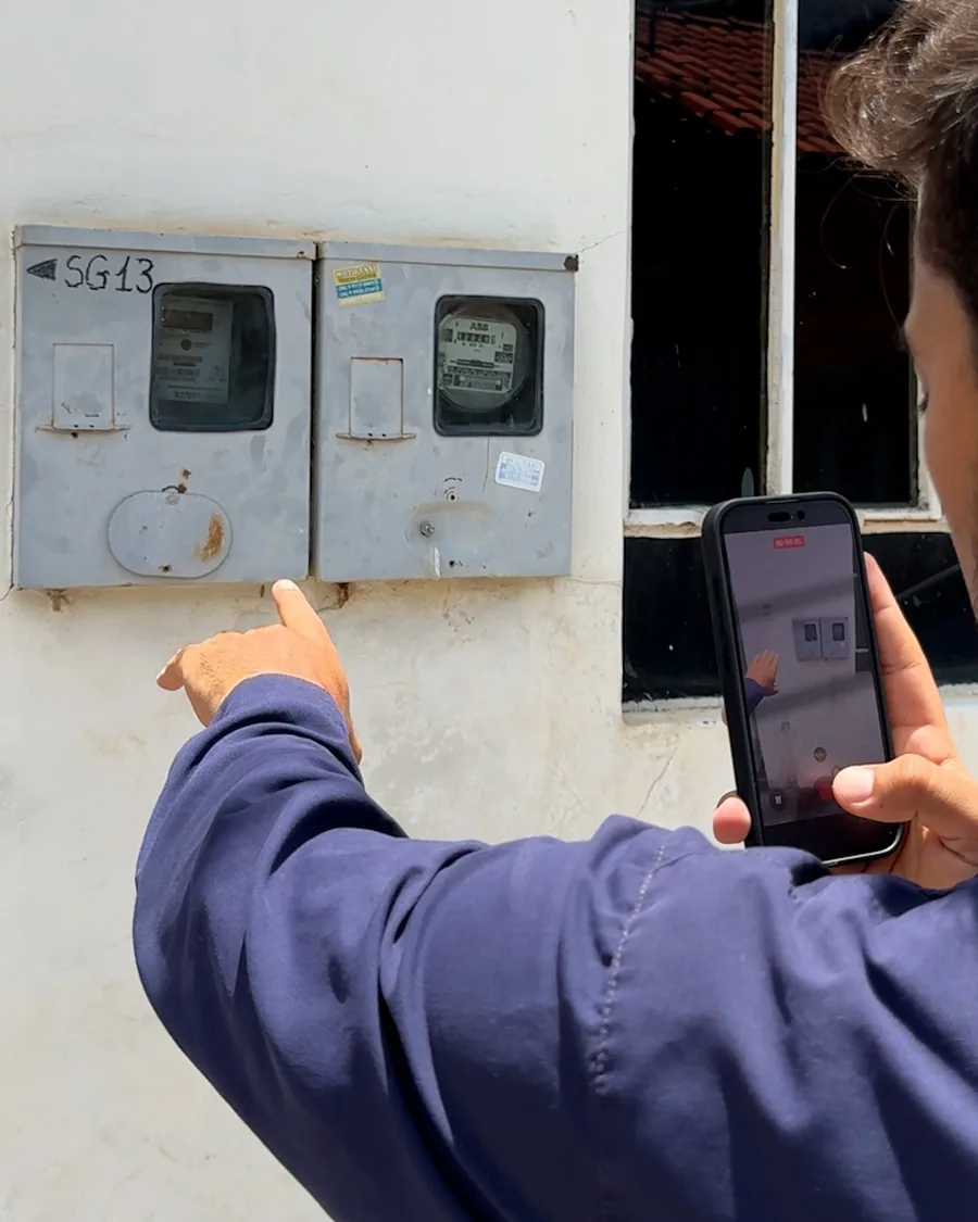 Técnico da HASE registrando com o celular o padrão de entrada e os medidores de energia do imóvel.